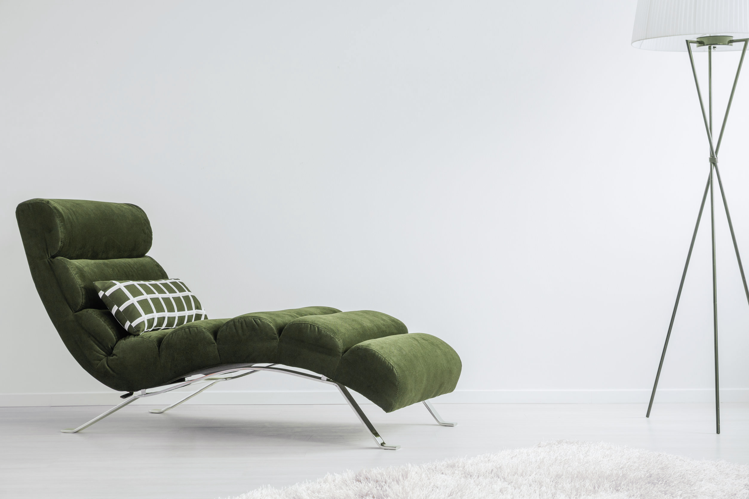 Modern metal lamp in psychologist's white room with geometric patterned pillow placed on dark settee